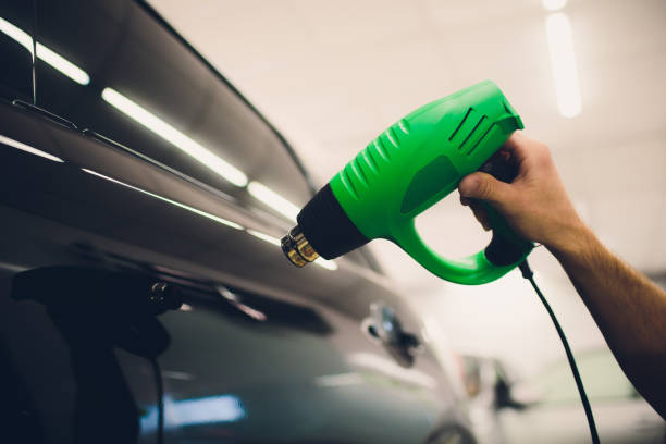 Master installs tint film for car with hairdryer. Concept protection car stock photo
