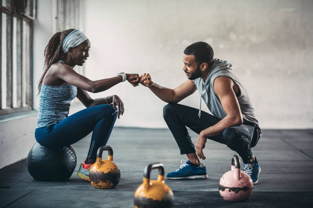 formateur et client féminin parlant dans la salle de gym - gym muscular build weights two people photos et images de collection