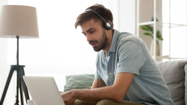 istock Serious focused man wearing headphones using laptop at home 1144036445
