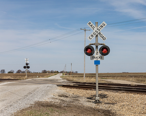 railroad crossing with warning sign and lights along a gravel road in the country