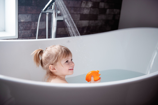 Cute little girl of 2-3 years old playing in a bathtub. Photo was taken in Quebec Canada