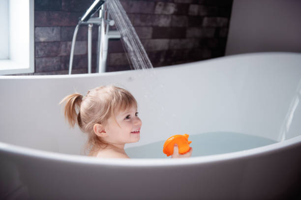 Cute little girl playing in a bathtub Cute little girl of 2-3 years old playing in a bathtub. Photo was taken in Quebec Canada girls bath stock pictures, royalty-free photos & images