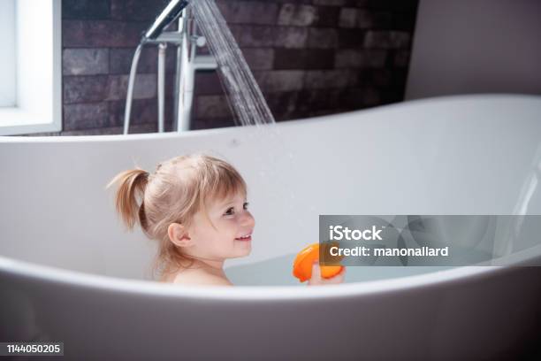 Cute Little Girl Playing In A Bathtub Stock Photo - Download Image Now - Bathtub, Child, Shower
