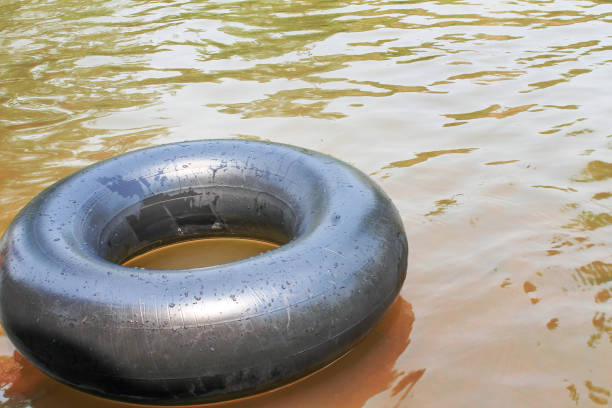 istock Old inner tubes with water drops and reflection from the sun floating on a river 1144055666