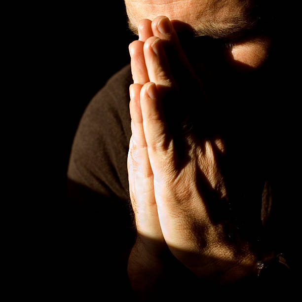 istock Man holding hands praying in the dark 114406115