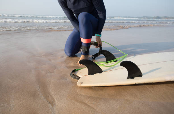 istock female surfer fastening leash across leg before going to surf 1144064736