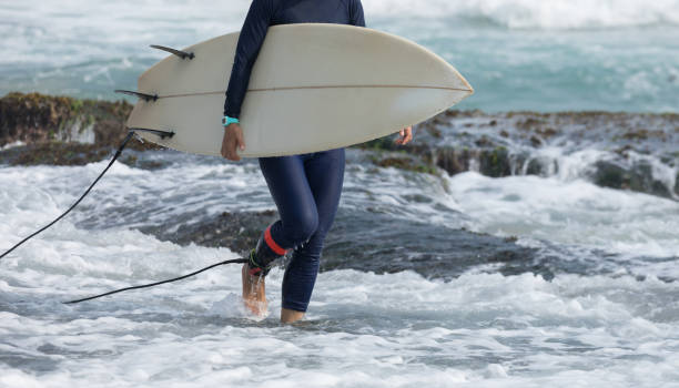 istock Woman surfer with surfboard going to surf 1144070518