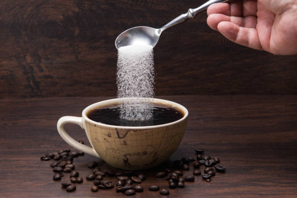 le sucre verse dans la cuvette de coffe avec des haricots de café sur le fond en bois - coffee hot drink cup teaspoon photos et images de collection