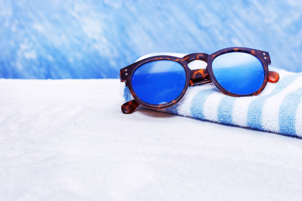 Sunglasses and cotton towel on sand beach with copy space.  Summer background.