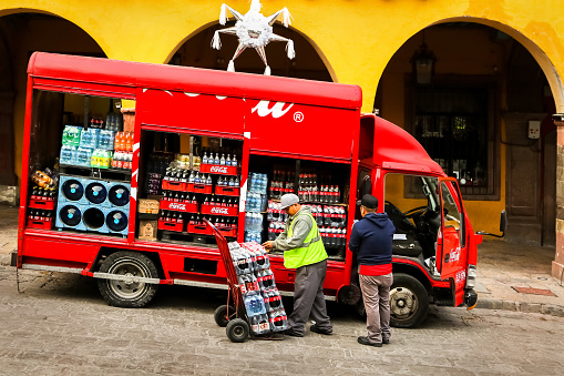 Mexico, San Miguel de Allende, Old Town - January 02, 2019: Workers unload bottles from Coca-Cola truck in the old town.