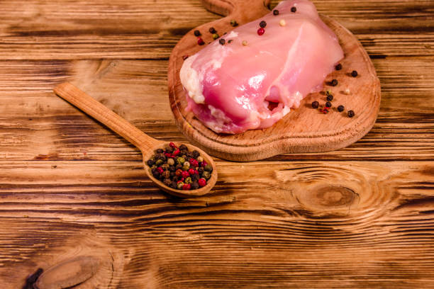 istock Cutting board with raw chicken fillet and spoon with different spices on wooden table 1144089148