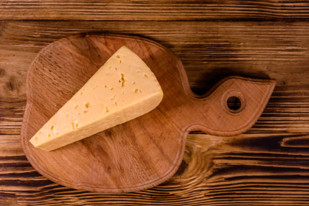 istock Cutting board with piece of cheese on wooden table. Top view 1144089149