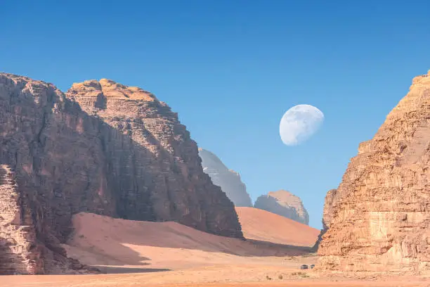 incredible lunar landscape with huge moon in Wadi Rum village in the Jordanian red sand desert. Wadi Rum also known as The Valley of the Moon,  Jordan - Image