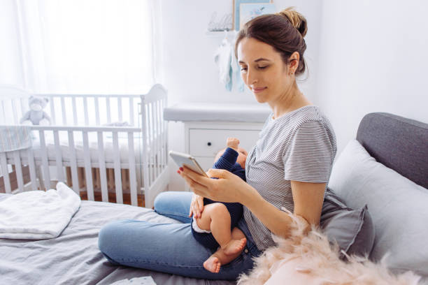 Mother breastfeeding baby Mother breastfeeding baby son in bedroom and using mobile phone 2 5 months photos stock pictures, royalty-free photos & images