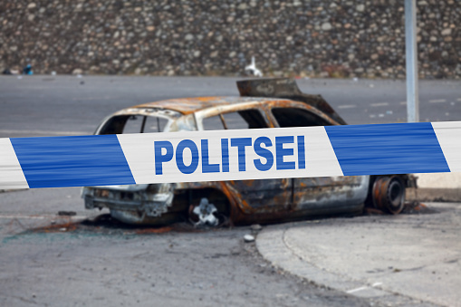 Car burnt by a pyromaniac with a police tape with written in it in Estonian \
