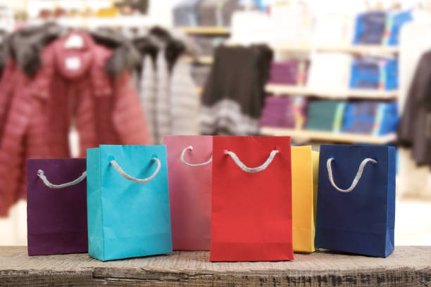 A lot of multi-colored paper shopping bags on a wooden table in a shop. Front view. stock photo