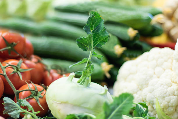 couve-rábano fresca em um mercado com tomates dos pepinos e couve-flor no fundo - kohlrabi turnip kohlrabies cabbage - fotografias e filmes do acervo