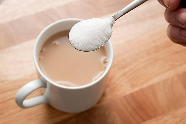 spoonful avec sucre sur tasse de thé - sucre semoule photos et images de collection