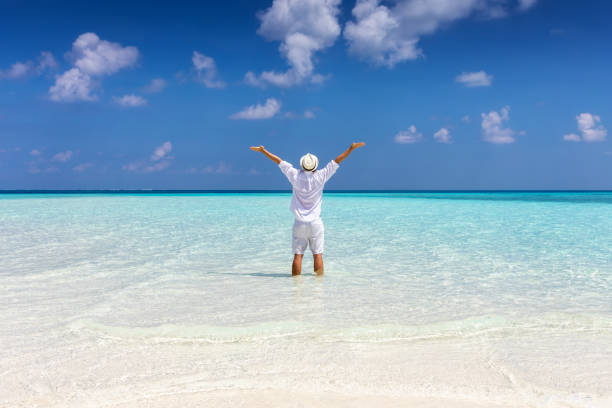 istock Man in white summer clothes stands on a tropical beach 1144122802