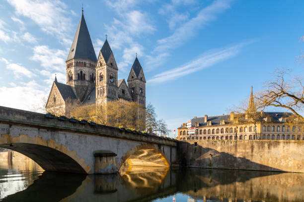 Pont des Roches bridge and Temple neuf - New Protestant church, German Imperial monument of Alsace-Lorraine in Ville de Metz city, Grand Est, France. Sun rays reflect in the waters of Moselle river stock photo