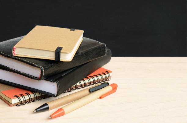 istock Notebooks and pens on wooden table with school black board 1144127469