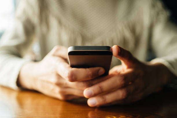 istock Woman using smartphone on wooden table in cafe 1144128537