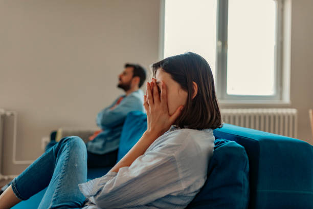 I can't believe we're fighting about this again... Unhappy Couple After an Argument in the Living Room at Home. Sad Pensive Young Girl Thinking of Relationships Problems Sitting on Sofa With Offended Boyfriend, Conflicts in Marriage, Upset Couple After Fight Dispute, Making Decision of Breaking Up Get Divorced spar stock pictures, royalty-free photos & images