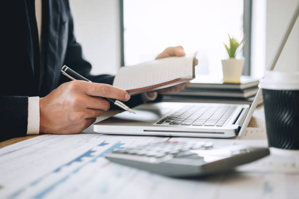 istock Businessman accountant working new project on laptop computer with report document and analyze document graph and diagram, doing finance making notes statistics 1144130945