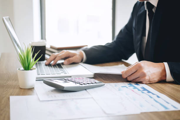 istock Businessman working new project on laptop computer with report document and analyze, calculating financial data on graph documents, doing finance making notes statistics 1144130979