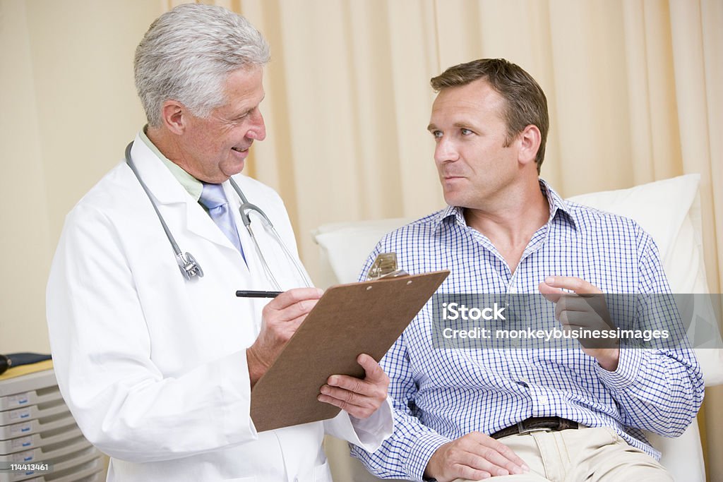 Medico scrivendo su Appunti dando checkup uomo - Foto stock royalty-free di Cinquantenne