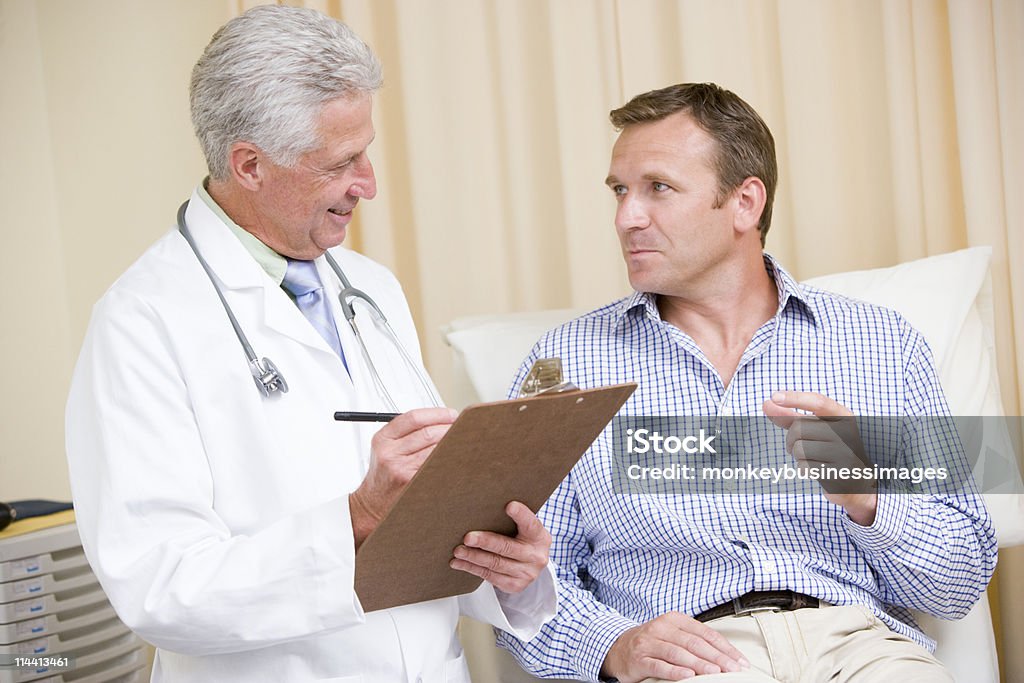 Médico escrevendo na área de transferência e concessão de homem verificação - Foto de stock de 50 Anos royalty-free