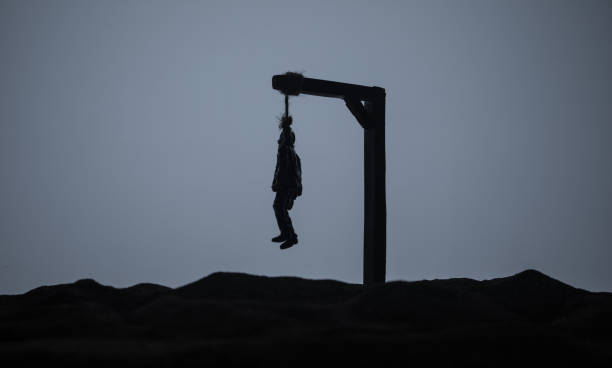 Horror view silhouette of hanged man on scaffold at misty evening with fog. Execution (or suicide) decoration. Horror Halloween concept. Selective focus