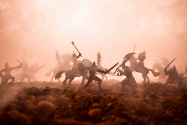 istock Medieval battle scene with cavalry and infantry. Silhouettes of figures as separate objects, fight between warriors on sunset foggy background. Selective focus 1144137899