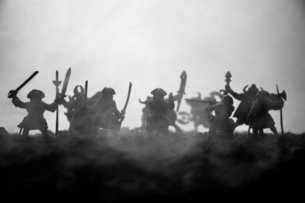 istock Medieval battle scene with cavalry and infantry. Silhouettes of figures as separate objects, fight between warriors on sunset foggy background. Selective focus 1144137911