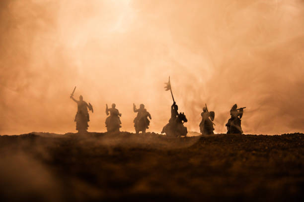 istock Medieval battle scene with cavalry and infantry. Silhouettes of figures as separate objects, fight between warriors on sunset foggy background. 1144137928