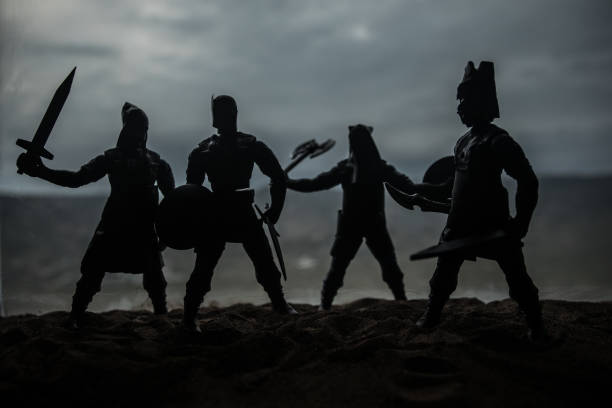 Medieval battle scene with cavalry and infantry. Silhouettes of figures as separate objects, fight between warriors on sunset foggy background. Artwork decoration. Selective focus
