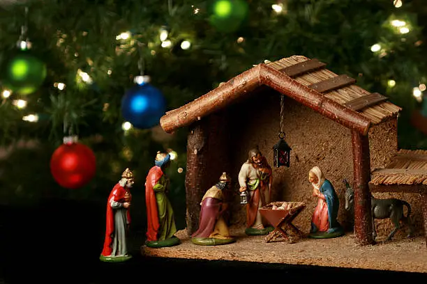 Photo of Nativity scene next to a Christmas tree