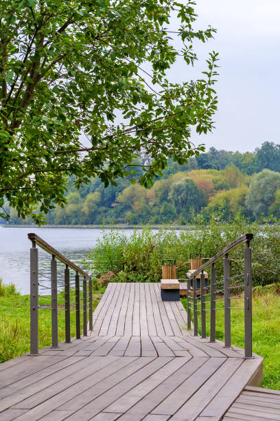 istock View on a wooden walking path with handrails in park on the river coast 1144142860