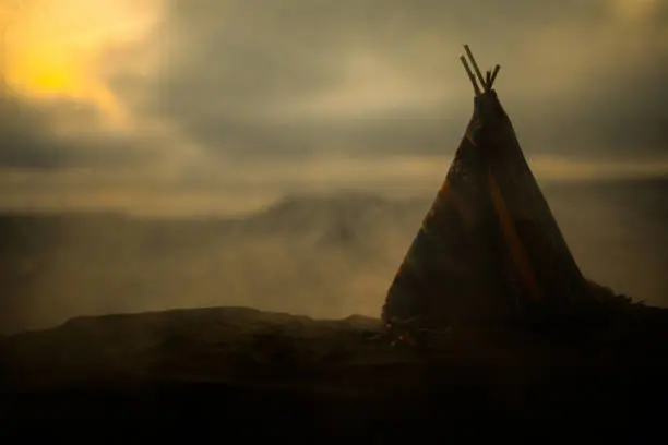 Artwork decoration creative concept. An old native american teepee in desert at the evening. Wigwam house indian style.