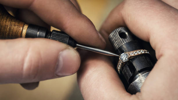 Jeweler repairing a gold ring, adjusting the gems on the product, close-up stock photo