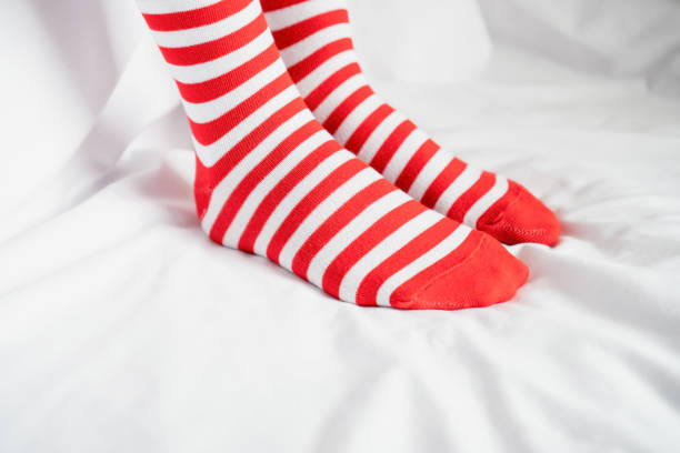 Women's legs in socks colors alternating, side stand on white fabric floor.