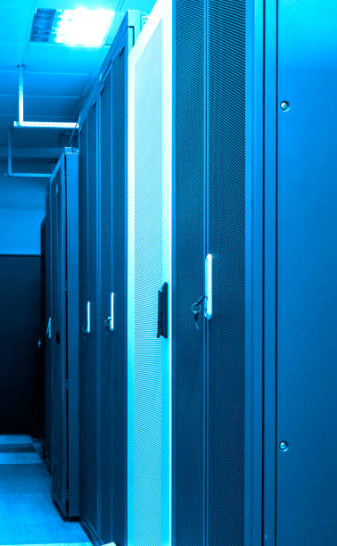 rzędy zamkniętych klastrów stojaków z serwerami i routerami w centrum dużych zbiorów danych z neonowym niebieskim tonowaniem. potężny internet, sprzęt telekomunikacyjny. serwerownia wewnątrz - network server rack data center in a row zdjęcia i obrazy z banku zdjęć