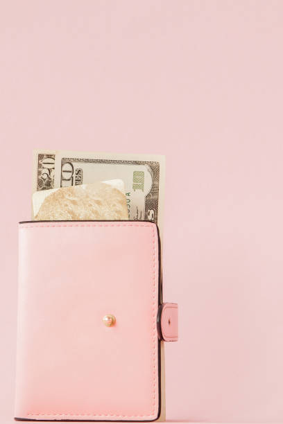 istock Dollars and pink wallet with credit card on pink background 1144150947