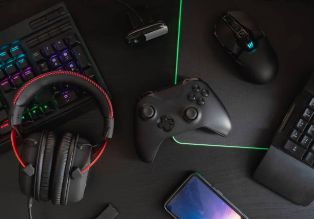 istock gamer workspace concept, top view a gaming gear, mouse, keyboard, joystick, headset, mobile joystick and mouse pad on black table background with RGB color. 1144153171