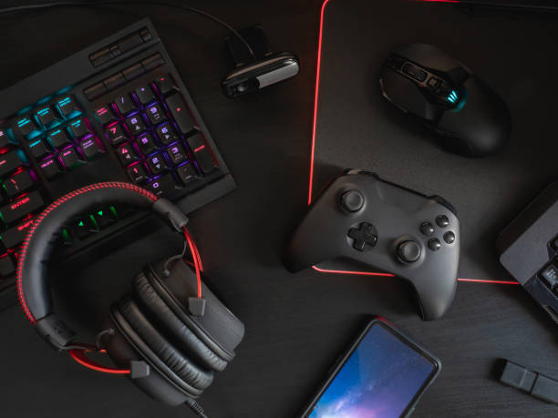 istock gamer workspace concept, top view a gaming gear, mouse, keyboard, joystick, headset, mobile joystick and mouse pad on black table background with RGB color. 1144153185