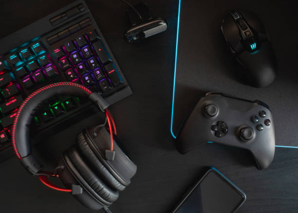 istock gamer workspace concept, top view a gaming gear, mouse, keyboard, joystick, headset, mobile joystick and mouse pad on black table background with RGB color. 1144153229