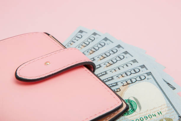 istock Purse with one hundred dollars banknotes on pink background. Flat lay, top view, copy space 1144153606