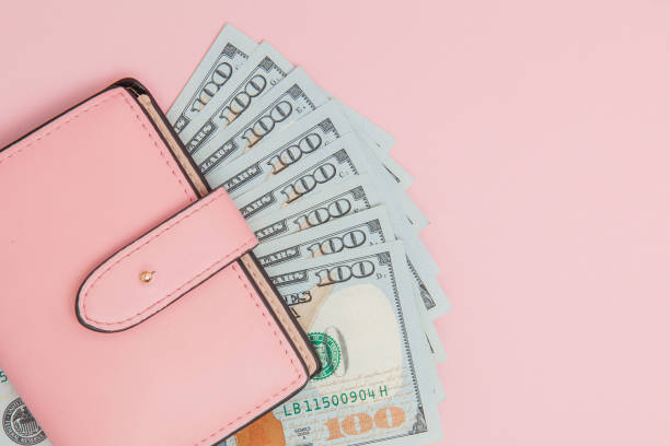 istock Purse with one hundred dollars banknotes on pink background. Flat lay, top view, copy space 1144153640