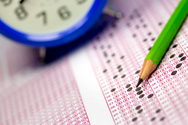 istock Students taking exams, writing examination room with holding pencil on optical form of standardized test with answers paper 1144161663