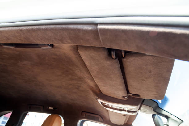 istock The ceiling of the SUV car pulled by brown soft material alkantara in the workshop for tuning and styling the interior, view from the passanger opened door on central mirror and sun visorson the roof 1144164298